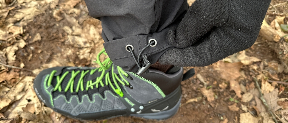 Eine Hand zieht den elastischen Beinabschluss der Maier Sports Nil Wanderhose fest. Die Funktion sorgt für besseren Sitz über Wanderstiefeln.