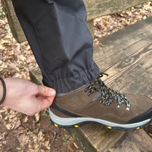 Eine Hand hält das Beinende der RevolutionRace Herren GPX Pro Hose hoch. Das Innenmaterial ist sichtbar und schützt vor Nässe und Schmutz.