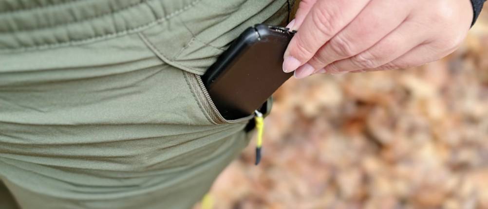 Die Hosentasche auf der linken Seite der Yeyity Wanderhose wird mithilfe des Reißverschlusses geöffnet und ein Handy passt hinein.