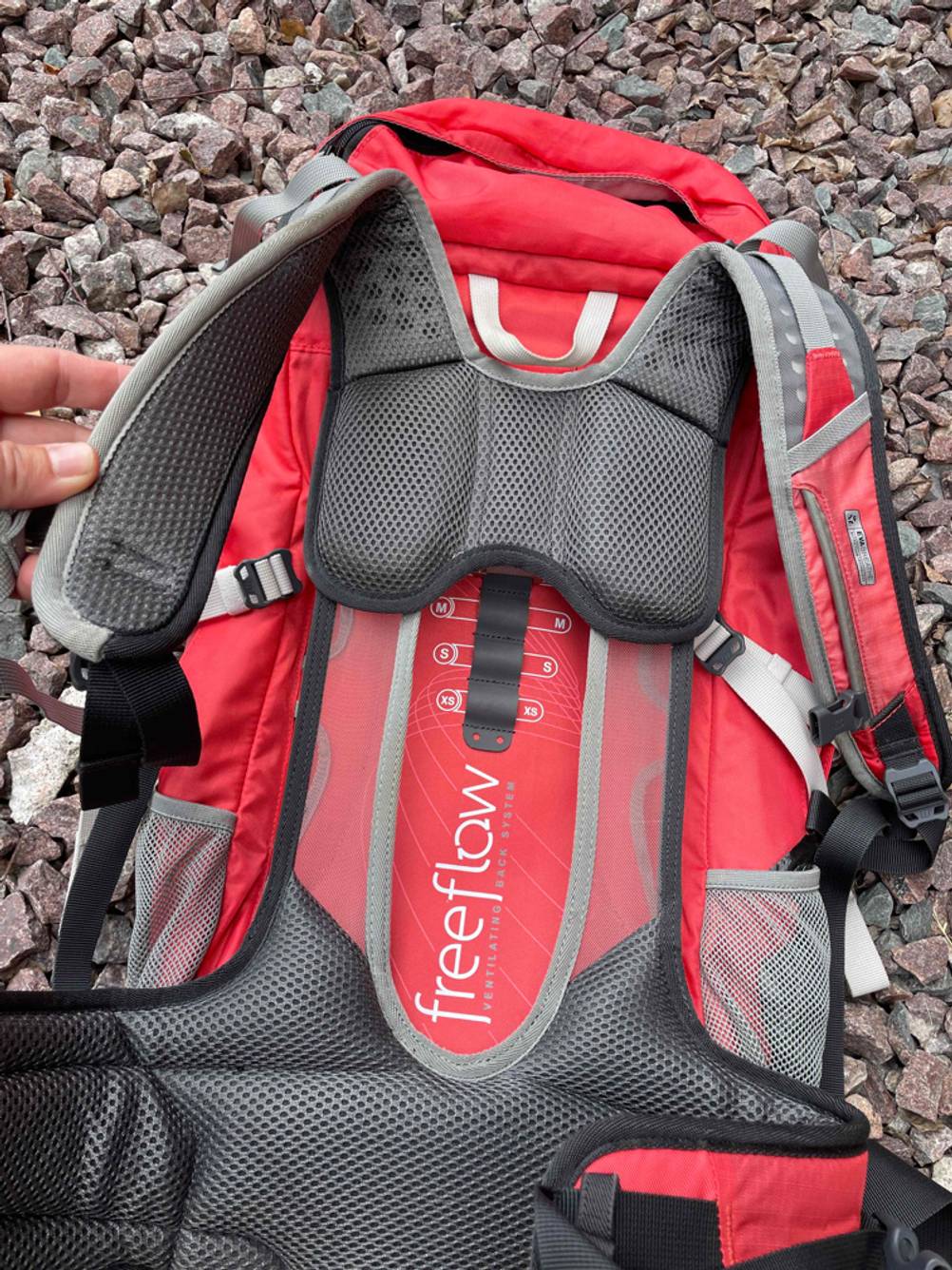 Wanderrucksack-Damen-Vergleich: Nahaufnahme der Polsterung von Rücken und Trägern eines Wanderrucksacks für Damen auf einem Kiesboden.