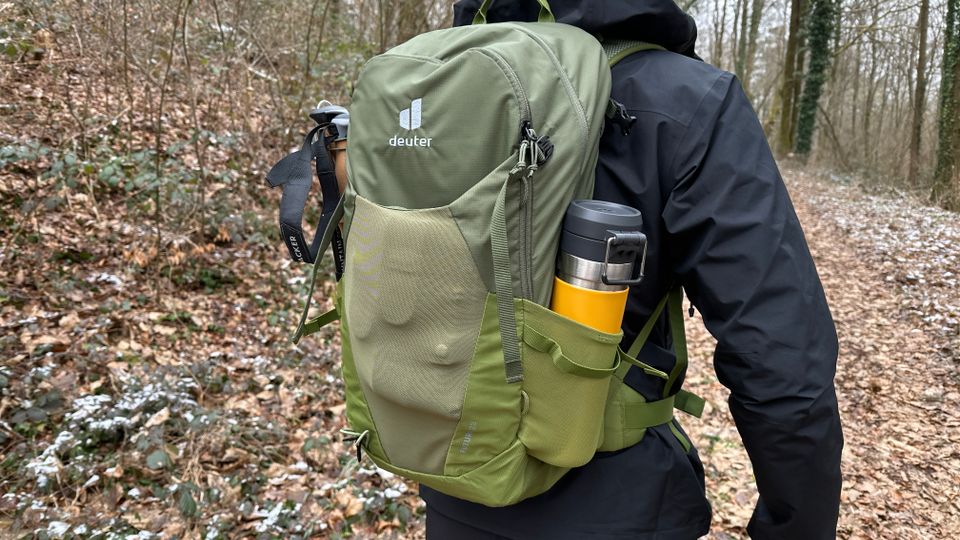 Der deuter Futura Wanderrucksack wird auf einer Wanderung getragen. In der Seitentasche steckt eine gelbe Thermoskanne.