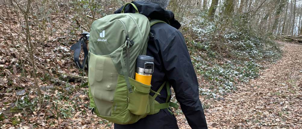 Ein Wanderer mit dem Deuter-Futura-Wanderrucksack ist auf einem Waldweg unterwegs. Der Rucksack wirkt kompakt und sitzt fest am Rücken.