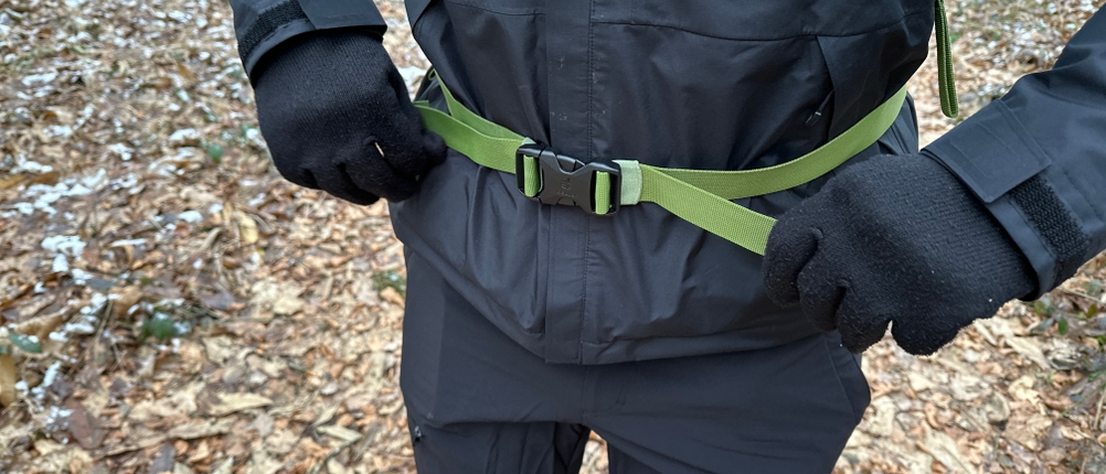 Der Hüftgurt des Deuter-Futura-Wanderrucksacks wird mit beiden Händen festgezogen. Der Gurt ist grün und verläuft über einer schwarzen Jacke.