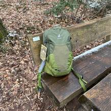 Der Deuter-Futura-Wanderrucksack steht auf einer Bank im Wald. Am Rucksack hängt ein Etikett mit Produktinformationen.