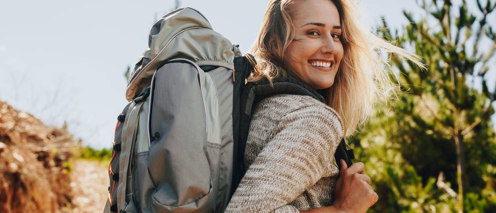 Wanderrucksack für Damen im Test: Frau in der Natur mit grauem Wanderrucksack.