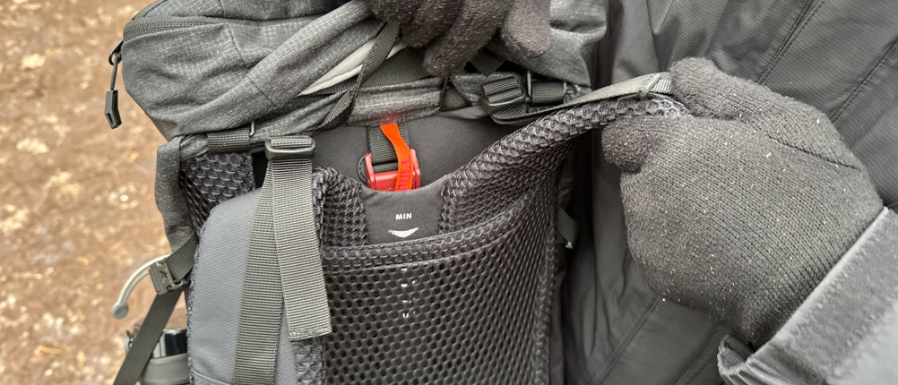 Eine Person passt am Vaude 14394 die Rückenlänge über ein integriertes Einstellsystem mit rotem Hebel an. Das System ist klar markiert.