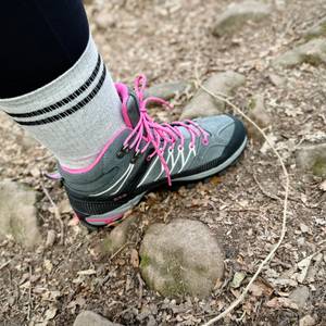 Wanderin mit CMP Rigel Mid unterwegs im Wald. Der Schuh steht auf erdigem, mit Laub bedecktem Untergrund.
