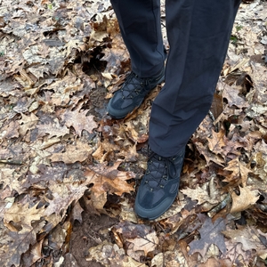 Der Jack Wolfskin Vojo 3 Texapore Mid M getragen im Wald auf feuchtem, laubbedecktem Boden. Die Schuhe sind vollständig geschnürt und einsatzbereit.
