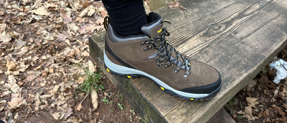 Seitenansicht des Skechers-Relment-Pelmo-Wanderschuhs auf einer Bank. Der mittelhohe Schaft ist deutlich zu erkennen.