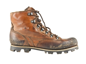 Ein einzelner, abgenutzter Wanderschuh im Retro-Stil mit tiefem Sohlenprofil. Das Leder ist stark beansprucht und teilweise verschmutzt.