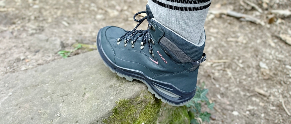Der Lowa Renegade EVO GTX MID im Einsatz auf einem Waldweg. Der Fuß steht auf einem mit Moos bedeckten Stein.