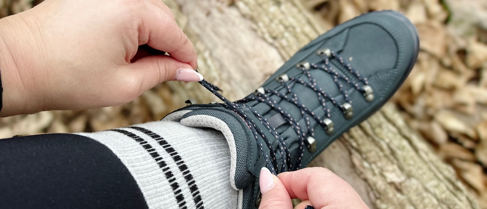 Der Lowa Renegade EVO GTX MID von oben. Eine Hand zieht die Schnürsenkel fest, die Schnürung ist vollständig geschlossen.