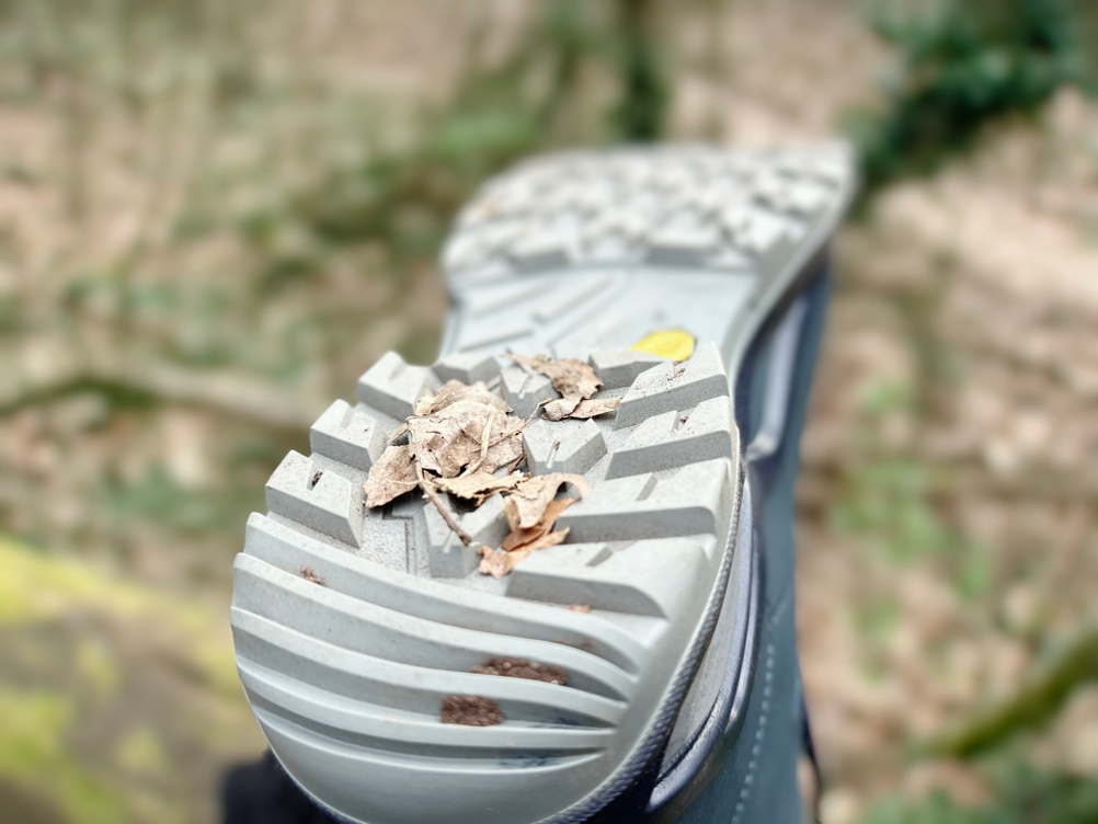 Verschmutzte Profilsohle des Lowa-Renegade-EVO-GTX-MID-Wanderschuhs mit Blättern im Profil, aufgenommen im Wald.