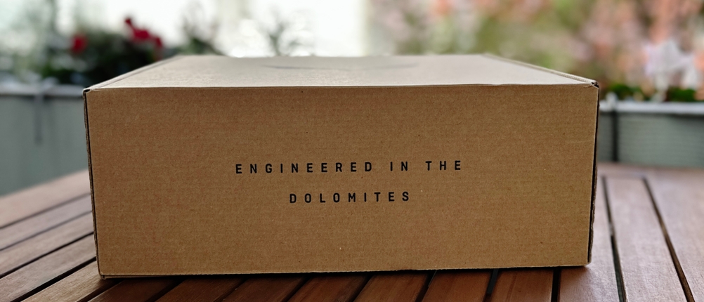 Salewa-Schuhkarton mit Aufschrift „Engineered in the Dolomites“ auf Holztisch. Die Verpackung ist geschlossen.