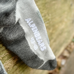 Nahaufnahme des Alpen Bears Logos auf den Wandersocken. Die weiße Schrift hebt sich deutlich vom grauen Material ab.