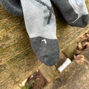 Eine Nahaufnahme der Alpen Bears Premium Wandersocken zeigt eine markierte Seitenkennzeichnung mit Richtungspfeilen und Größenangabe.