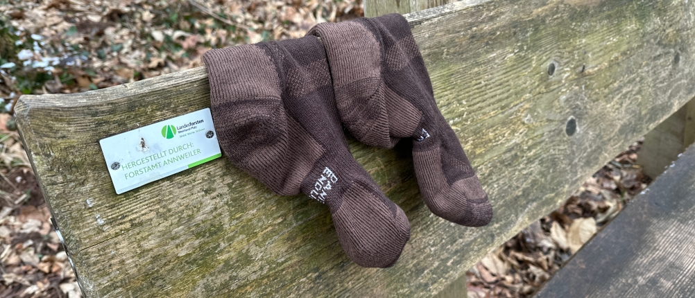 Ein Paar Danish Endurance Merino Wandersocken liegt nach dem Gebrauch auf einer Holzbank. Die Struktur der Wolle und mögliche Abnutzungsspuren sind erkennbar.
