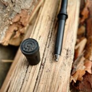 Die Spitze eines Alpen Bears Wanderstocks liegt neben einem Gummipuffer auf Holz. Beide Komponenten sind demontiert dargestellt.