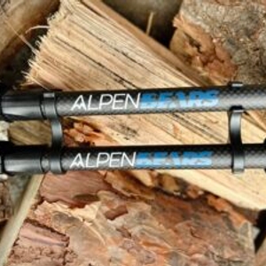 Zwei zusammengeklappte Alpen Bears Wanderstöcke liegen nebeneinander auf einem Holzstapel. Die Logos sind gut erkennbar.