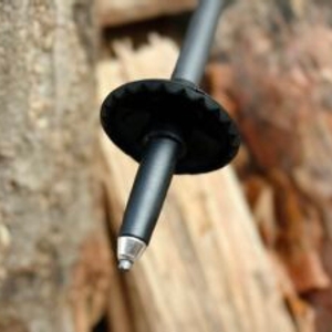 Detailansicht der Spitze eines Alpin Loacker Wanderstocks mit befestigtem Trekkingteller. Die Metallspitze ist deutlich erkennbar und zeigt die Stockunterseite.