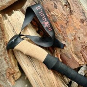 Nahaufnahme des Griffs eines Rothwild Teleskopstocks aus Carbon mit Korkgriff und Schlaufe auf Holzuntergrund.