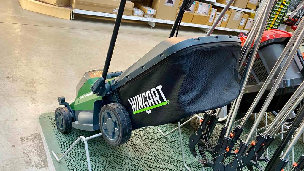 Wingart Akku-Rasenmäher im Test von hinten, mit Fokus auf den Auffangkorb in einem Geschäft mit weiteren Warengütern.