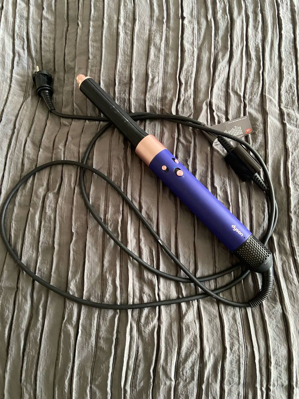 Die getestete Warmluftbürste mit Kabel auf einem Stoff liegend.