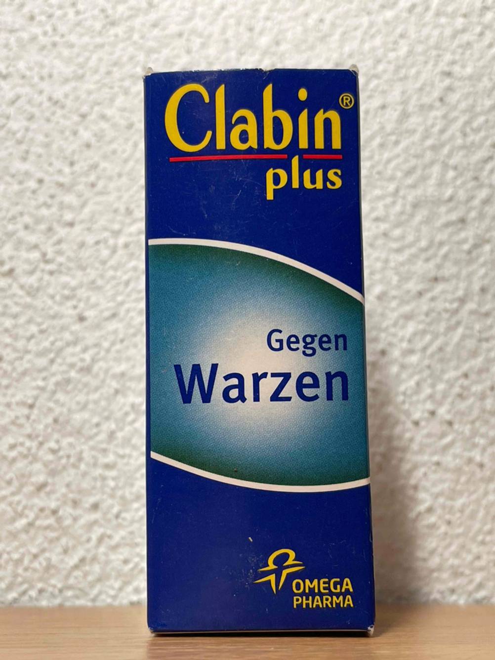 Die Originalverpackung des Warzenmittels im Test vor einer hellen Wand.
