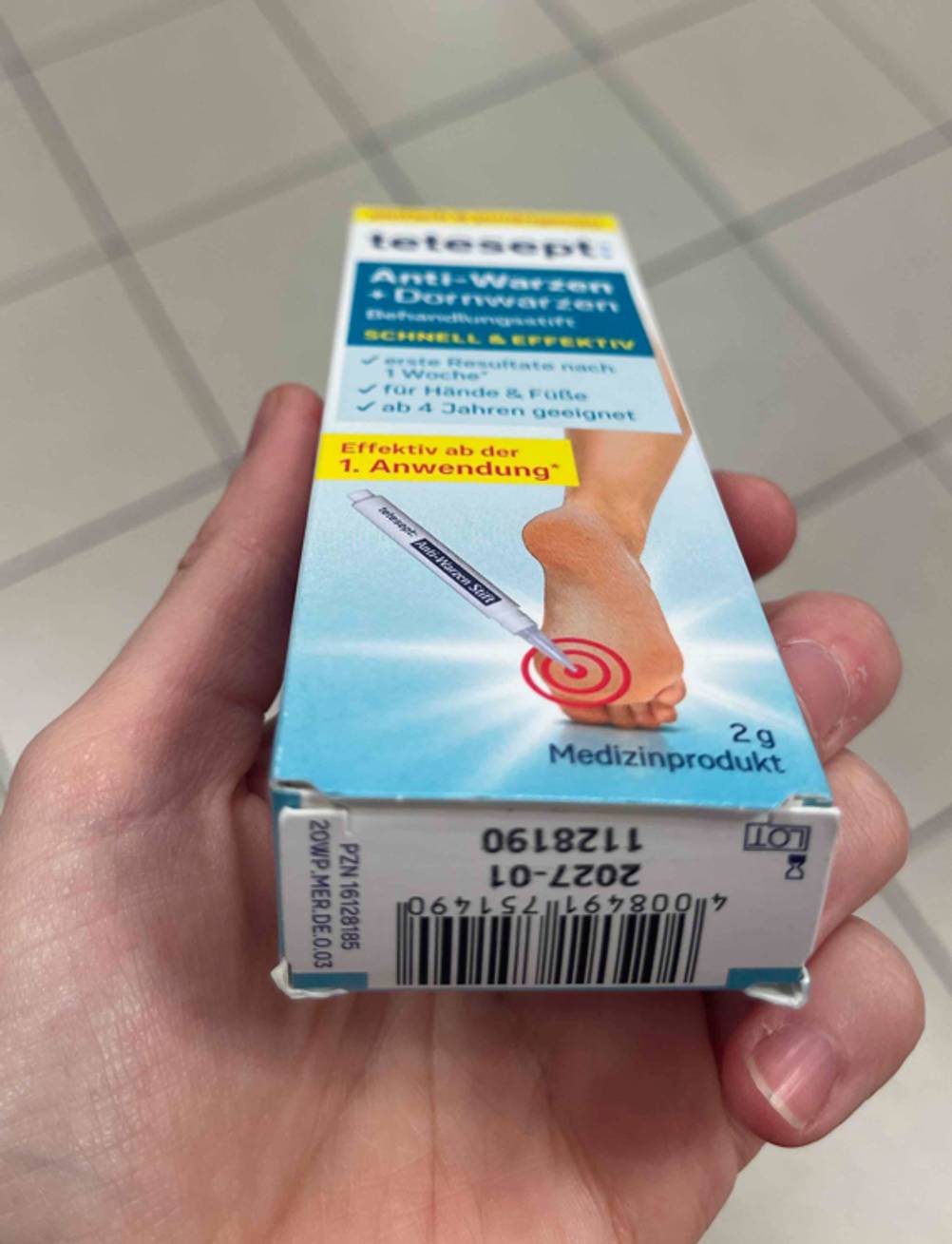 Eine Hand zeigt das Verfallsdatum auf dem Boden der Verpackung von Tetesept, in der sich der getestete Warzenstift befindet.