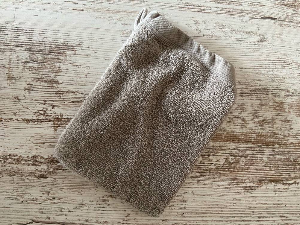 Der getestete Waschhandschuh auf einer Holzfläche liegend.