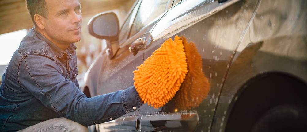 Waschhandschuh-Test: Ein Mann wäscht das Auto mit einem Waschhandschuh.