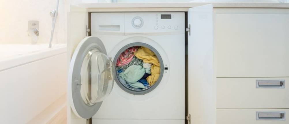 Energiesparende-Waschmaschine-Test: Frontlader steht mit offener Tür und voller Wäschetrommel in einer Ecke im Raum