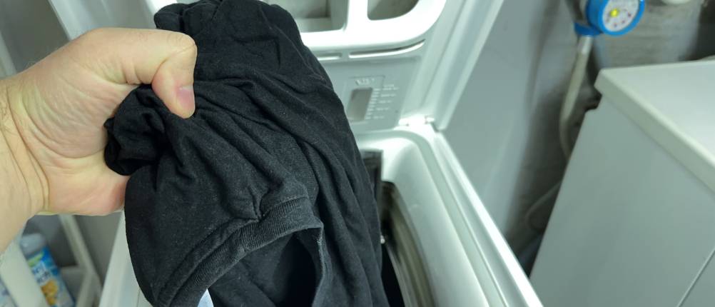 Dunkle Wäsche wird in eine Waschmaschine gefüllt.