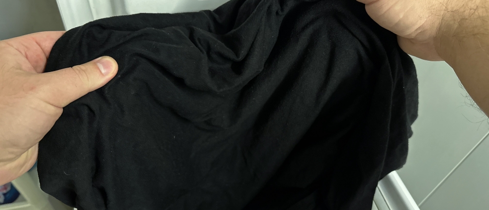 Ein gewaschenes schwarzes T-Shirt wird aus der Waschmaschine genommen.