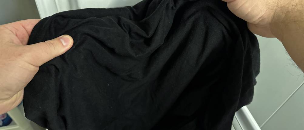 Ein gewaschenes schwarzes T-Shirt wird aus der Waschmaschine genommen.