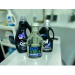 Waschmittel für schwarze Wäsche von Coral, Perwoll und Ecover stehen auf einer Waschmaschine.