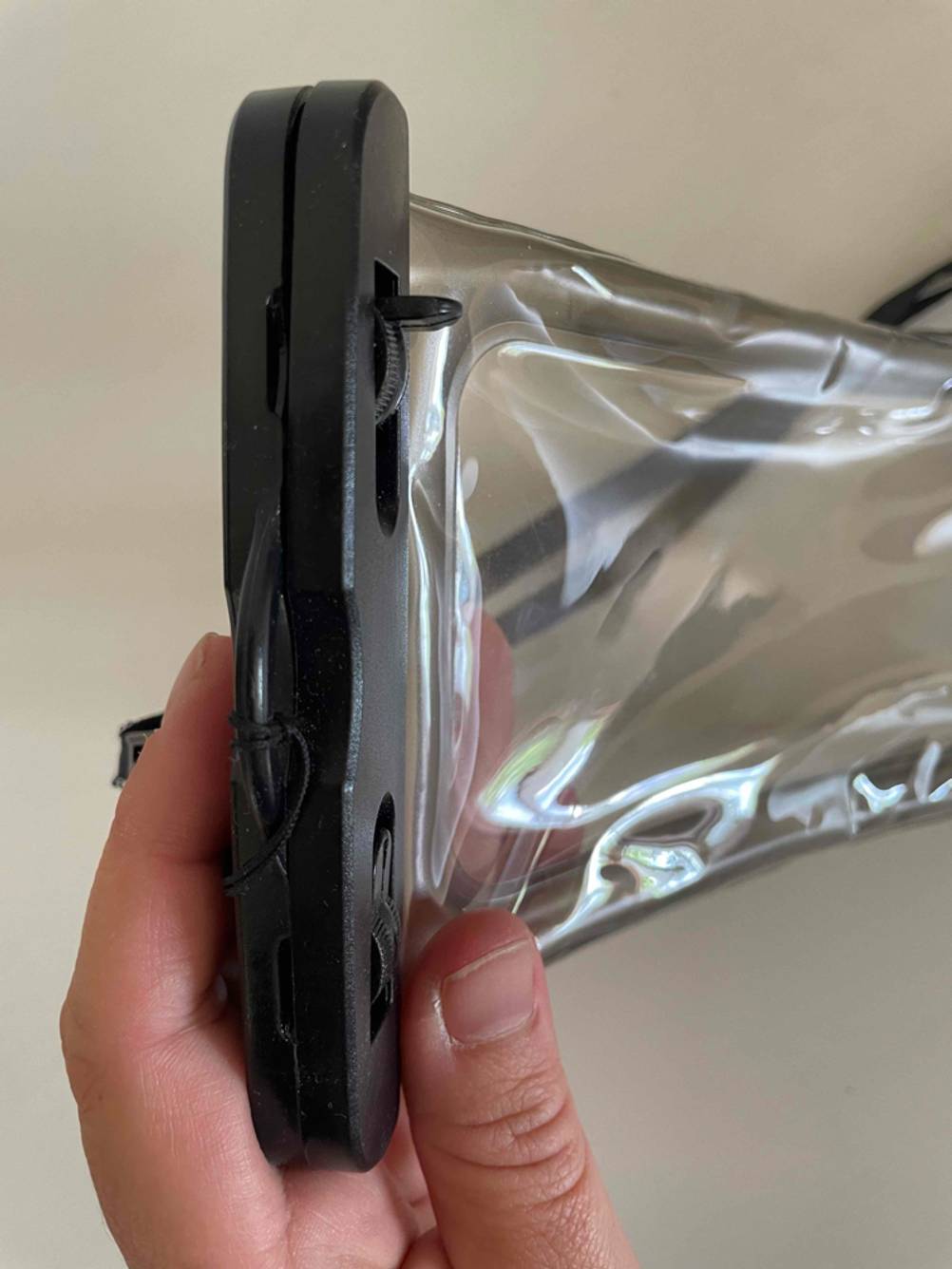 Im Test: Eine Hand hält eine geschlossene wasserdichte Handyhülle mit Fokus auf die Räder zum Festziehen.