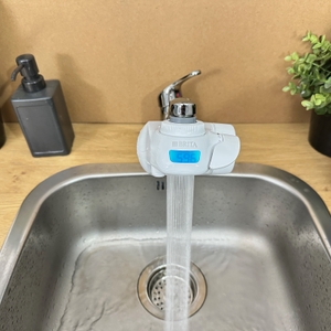 Aus einem montierten Brita-Wasserfilter läuft ein Wasserstrahl.