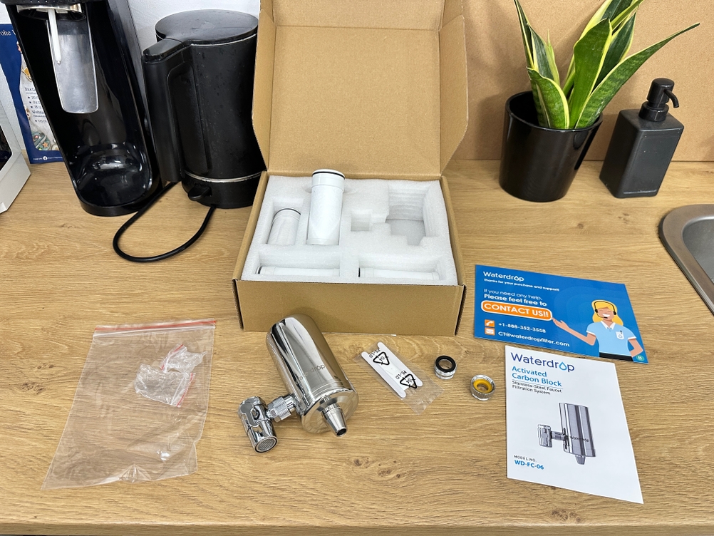 Der Lieferumfang eines Waterdrop-Wasserfilters liegt auf einem Tisch.