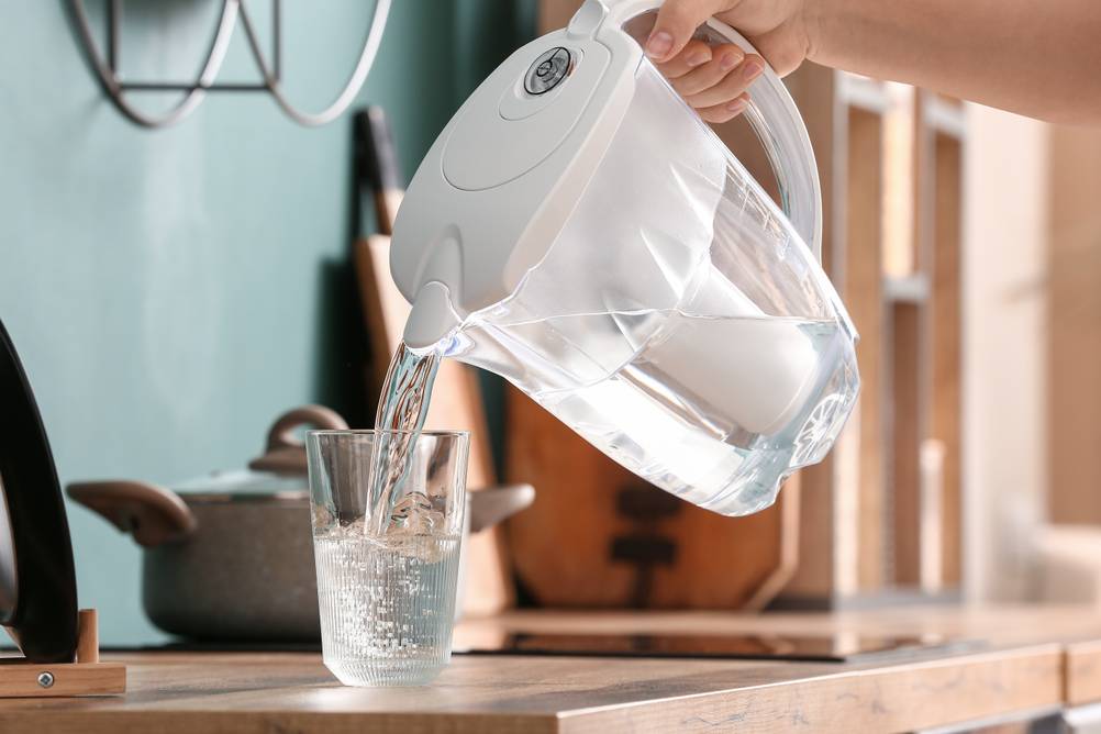 Wasser aus einer Filterkanne wird in ein Glas gegossen