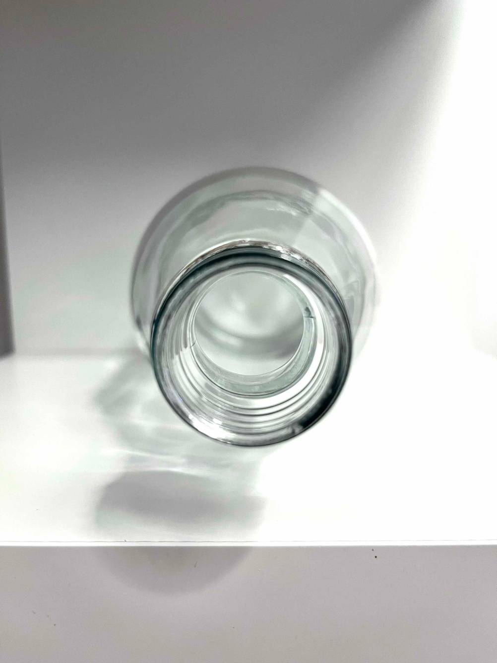 Eine getestete Wasserkaraffe mit der Öffnung nach vorne auf einem weißen Regal liegend.