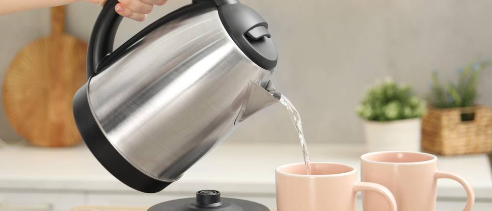 Wasserkocher-Tefal-Test: Person gießt heißes Wasser aus dem Wasserkocher in eine Tasse ein.