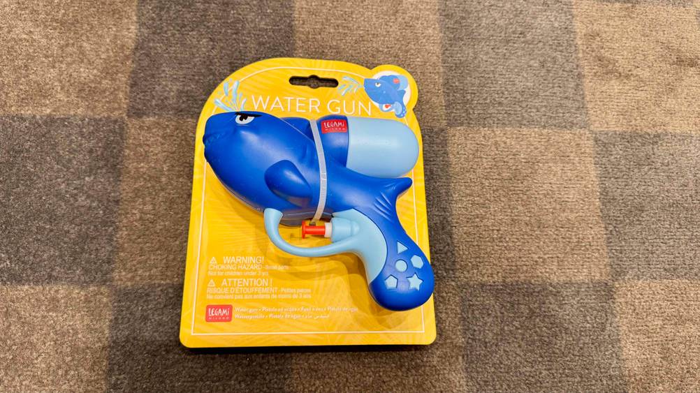 Die getestete Wasserpistole liegt auf einem Teppichboden.