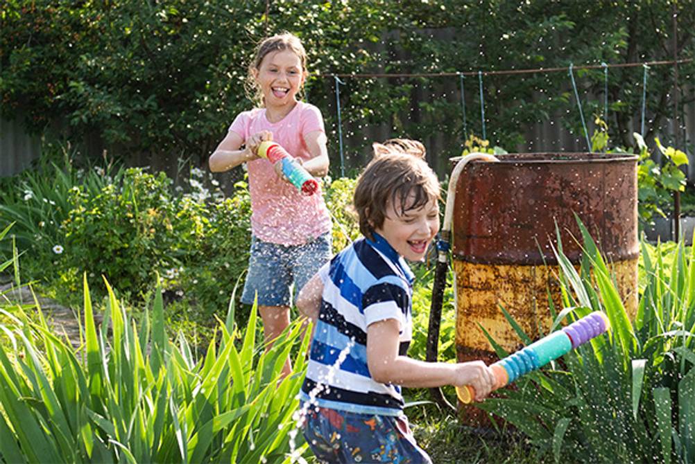 Wasserspritze im Test: Ein Junge und ein Mädchen bei einer Wasserschlacht mit Wasserspritzen im Garten.