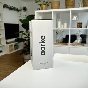 Seitliche Ansicht der Verpackung des Aarke Carbonator 3 mit Produktbezeichnung und schlichtem Design. Der Karton steht auf einem weißen Tisch.