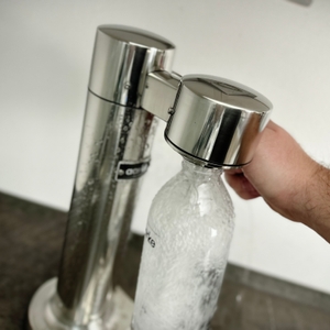 Eine Flasche mit sprudelndem Wasser am Aarke Carbonator 3 zeigt Kohlensäure, die aus der Düse spritzt.