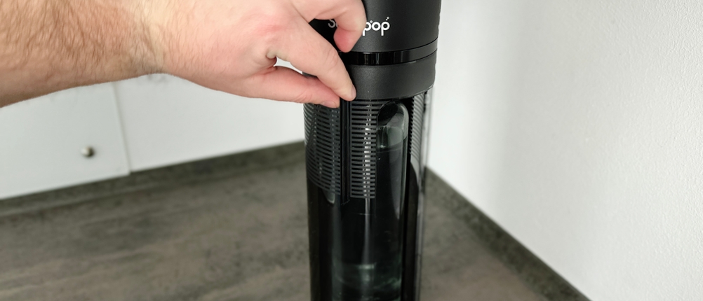 Eine Hand öffnet die Schiebetür des Sodapop Logan. Dahinter befindet sich die eingesetzte Flasche.