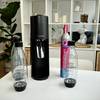 Der Sodastream Terra mit zwei Flaschen und einer CO₂-Kartusche auf einem Tisch. Das Gerät steht aufrecht, die Flaschen und der Zylinder sind daneben platziert.