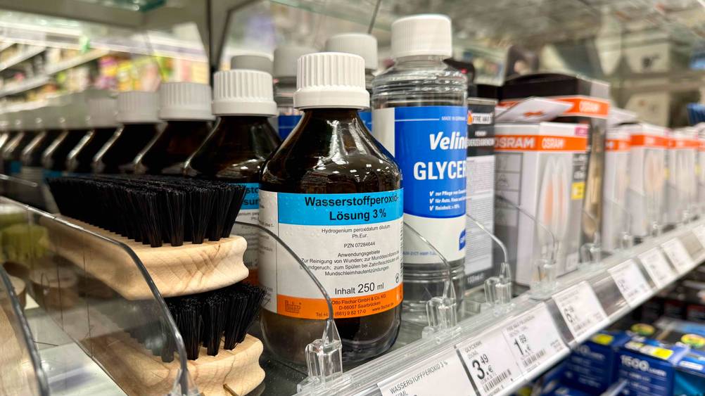 Mehrere Flaschen des getesteten Wasserstoffperoxid 3 Prozent neben anderen Produkten in einem Verkaufsregal.
