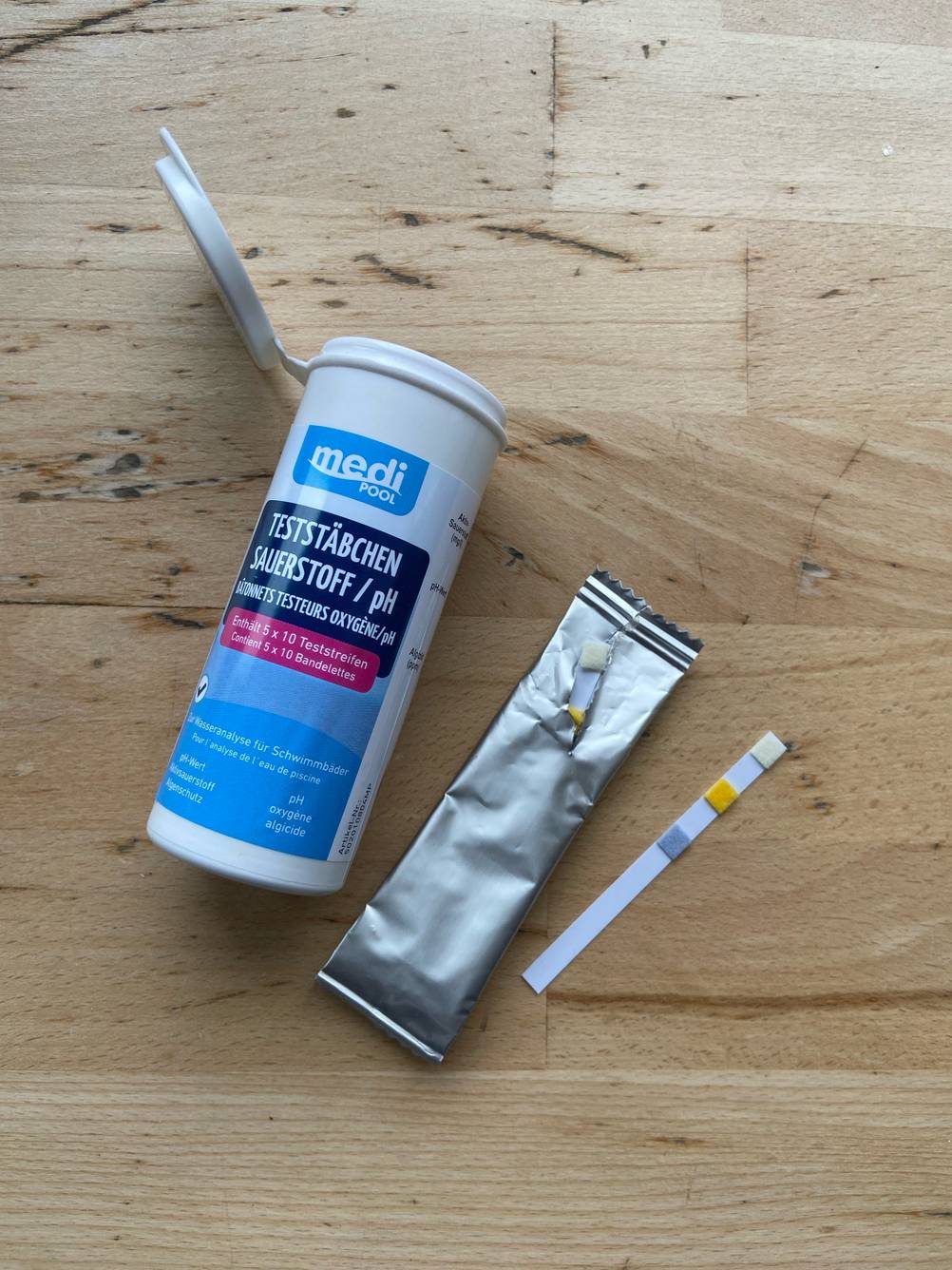 Wasserteststreifen getestet: Auf einem Holztisch liegt der Wasserteststreifen neben der Verpackung und der Aufbewahrungsdose.